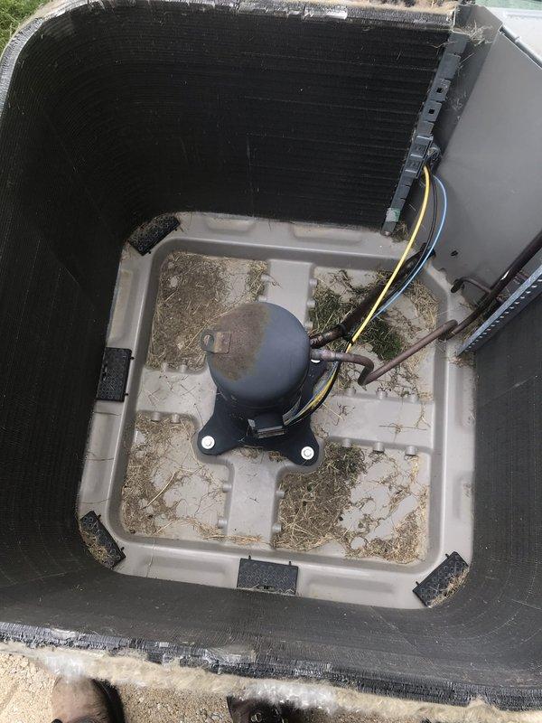 Completed preventive maintenance tune-up on outdoor air conditioning system. Inspected compressor assembly, electrical connections, and refrigerant lines; noted significant accumulation of environmental debris including leaves, grass clippings, and dirt in drain pan and on condenser coil fins. Cleaned accessible components, verified proper compressor operation, and documented unit condition with photographic evidence for service records.