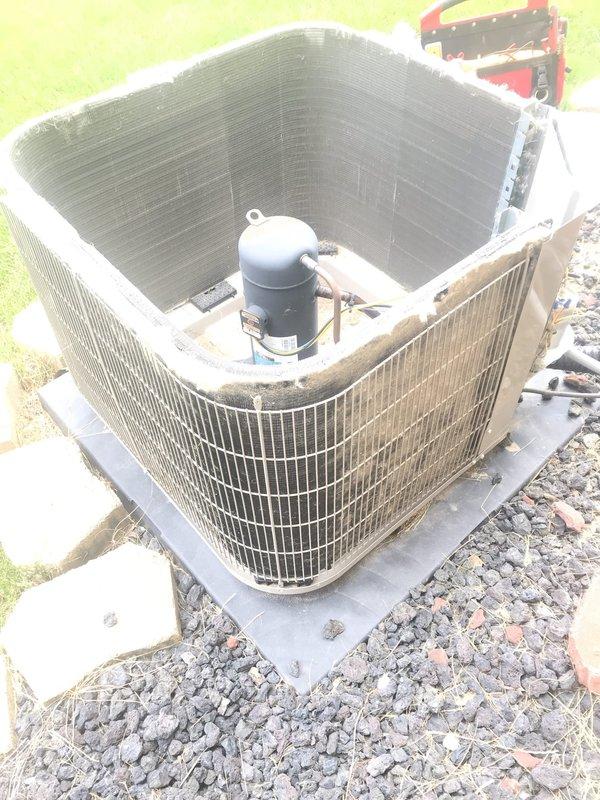 Completed preventive maintenance tune-up on outdoor air conditioning system. Inspected compressor assembly, electrical connections, and refrigerant lines; noted significant accumulation of environmental debris including leaves, grass clippings, and dirt in drain pan and on condenser coil fins. Cleaned accessible components, verified proper compressor operation, and documented unit condition with photographic evidence for service records.