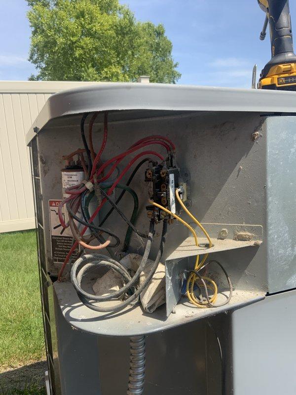 # No Cooling - 20 Year Old Central AC System

Responded to no cooling call on residential central air conditioning system approximately 20 years old. Upon arrival, confirmed entire home was without cooling. Accessed outdoor condensing unit and removed service panel to inspect electrical and mechanical components.

Performed visual inspection of contactor, capacitor, and wiring connections. Found aged wiring with accumulated dirt and weathering consistent with unit age. Checked electrical connections at contactor terminals, noting multiple red power wires, ground wire, and control wiring. Inspected dual run capacitor mounted in outdoor unit compartment.

Conducted diagnostic testing to determine root cause of no cooling condition. Evaluated compressor operation, contactor function, and capacitor performance. Assessed refrigerant system for potential leaks or charge issues as requested.

Given the advanced age of the equipment at 20 years old, discussed system condition and repair versus