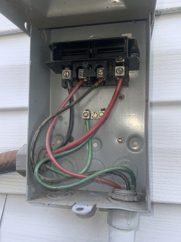 # HVAC Service Call - No Cooling Issue

Responded to service call for minimal cooling despite outdoor unit operation in manufactured home with aging air conditioning system. Customer reported very little cool air indoors while outside unit appeared to run normally, with suspected issue in indoor components.

Upon arrival, performed comprehensive system diagnostic starting with outdoor unit inspection. Examined electrical disconnect box mounted on exterior, noting weathered condition consistent with system age. Inspected internal wiring connections at disconnect, finding disorganized wire routing with multiple conductors in red, black, and green insulation. Assessed contactor assembly showing significant age-related wear, dust accumulation, and surface corrosion on brass terminal screws.

Evaluated contactor switching mechanism and internal contact points for proper operation. Examined all wire terminations including those with yellow crimp connectors at lower terminals. Verified electr