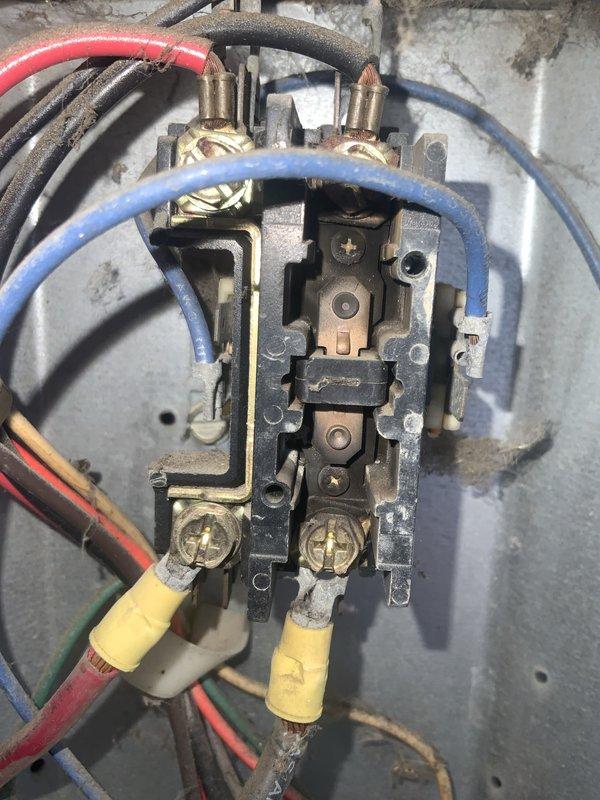 # HVAC Service Call - No Cooling Issue

Responded to service call for minimal cooling despite outdoor unit operation in manufactured home with aging air conditioning system. Customer reported very little cool air indoors while outside unit appeared to run normally, with suspected issue in indoor components.

Upon arrival, performed comprehensive system diagnostic starting with outdoor unit inspection. Examined electrical disconnect box mounted on exterior, noting weathered condition consistent with system age. Inspected internal wiring connections at disconnect, finding disorganized wire routing with multiple conductors in red, black, and green insulation. Assessed contactor assembly showing significant age-related wear, dust accumulation, and surface corrosion on brass terminal screws.

Evaluated contactor switching mechanism and internal contact points for proper operation. Examined all wire terminations including those with yellow crimp connectors at lower terminals. Verified electr