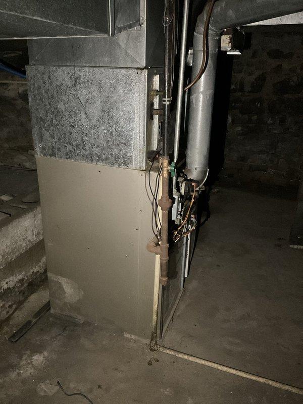 Conducted on-site evaluation of existing HVAC system in basement mechanical room to provide replacement estimate. Inspected aging furnace unit with galvanized metal upper section showing significant dust accumulation and wear. Documented current system configuration including cylindrical supply duct, electrical panel connections, and copper refrigerant lines. Photographed equipment specifications, manufacturer labels, and overall installation layout to prepare comprehensive quote for complete system replacement. Assessed ductwork condition and electrical service compatibility for new equipment installation.