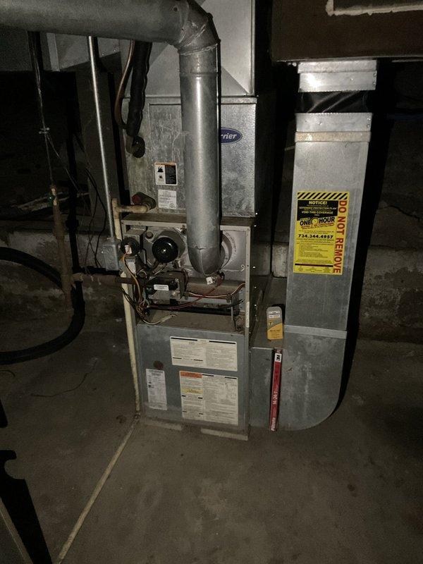 Conducted on-site evaluation of existing HVAC system in basement mechanical room to provide replacement estimate. Inspected aging furnace unit with galvanized metal upper section showing significant dust accumulation and wear. Documented current system configuration including cylindrical supply duct, electrical panel connections, and copper refrigerant lines. Photographed equipment specifications, manufacturer labels, and overall installation layout to prepare comprehensive quote for complete system replacement. Assessed ductwork condition and electrical service compatibility for new equipment installation.
