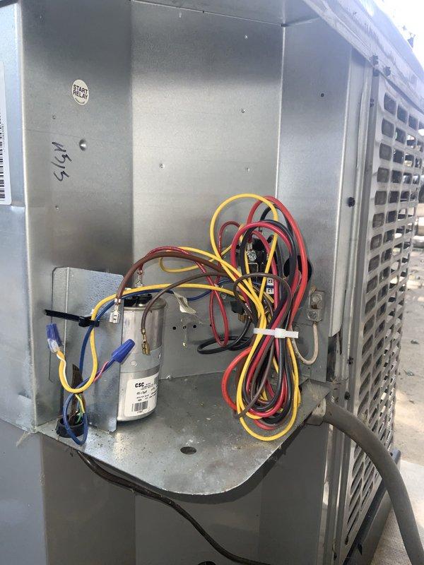 Responded to no cooling complaint on aging air conditioning system experiencing ice buildup on evaporator coil. Upon inspection, found unit icing over due to restricted airflow and low refrigerant charge. Removed access panels to assess electrical components and control systems. Verified capacitor operation and electrical connections at both outdoor condensing unit and indoor air handler. Checked all wire terminals and control board functionality. Documented existing equipment condition showing typical wear for system age. Performed diagnostic testing of electrical circuits and control sequences. System required defrost cycle completion before further diagnostics could be performed. Captured detailed photos of internal components including wiring harness, capacitor assembly, and control board configuration for service records.