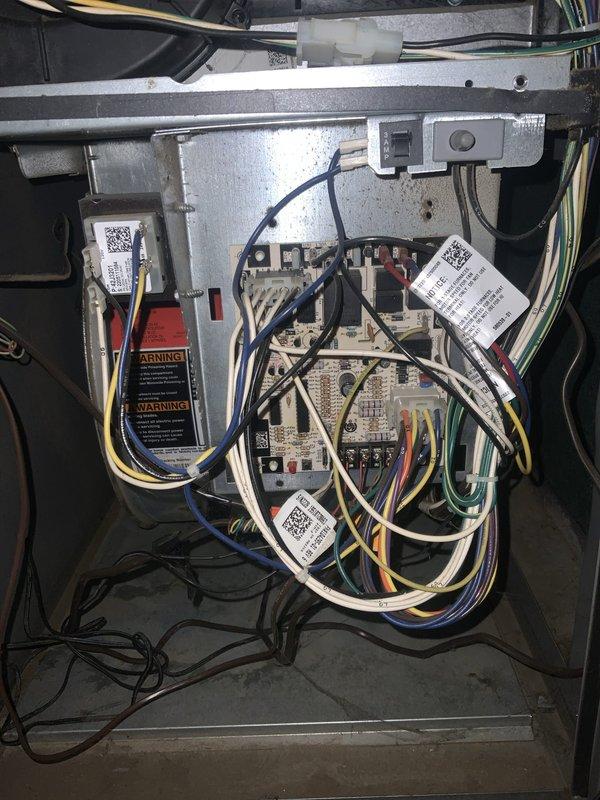 Responded to no cooling complaint on aging air conditioning system experiencing ice buildup on evaporator coil. Upon inspection, found unit icing over due to restricted airflow and low refrigerant charge. Removed access panels to assess electrical components and control systems. Verified capacitor operation and electrical connections at both outdoor condensing unit and indoor air handler. Checked all wire terminals and control board functionality. Documented existing equipment condition showing typical wear for system age. Performed diagnostic testing of electrical circuits and control sequences. System required defrost cycle completion before further diagnostics could be performed. Captured detailed photos of internal components including wiring harness, capacitor assembly, and control board configuration for service records.