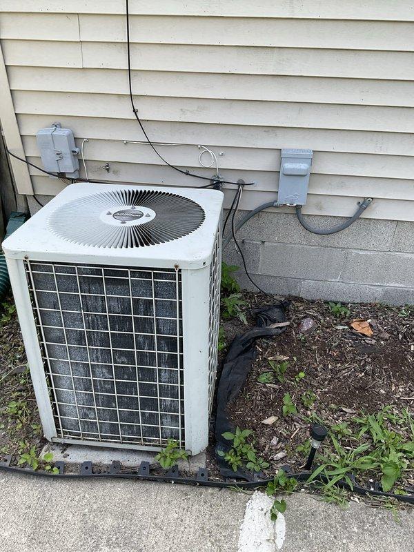Performed estimate visit for HVAC system replacement. Documented existing outdoor air conditioning condenser unit mounted on concrete pad with visible weathering and dirt accumulation, along with electrical disconnect boxes and conduit connections. Assessed indoor Distinctions brand furnace installation in utility area with associated PVC venting, ductwork, and filter housing. Photographed both outdoor and indoor equipment to provide comprehensive system evaluation for replacement proposal.