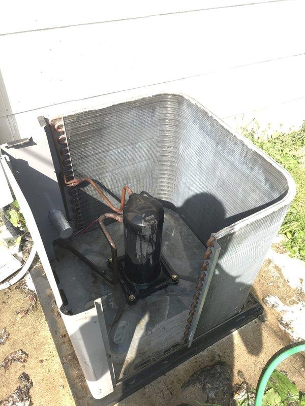 Responded to no-cool service call on 10+ year old outdoor condenser unit located behind residence with reported non-spinning blades. Upon arrival, removed top panel and performed visual inspection of internal components including condenser coil, compressor, and refrigerant lines. Inspected fan motor assembly and blade mechanism to diagnose failure cause. Photographed unit condition showing condenser coil, compressor with copper line connections, and overall equipment installation on concrete pad. Unit assessed for operational status and component functionality to determine necessary repairs for restoring cooling operation.