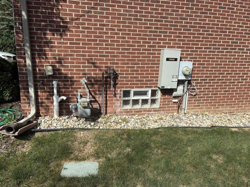 Conducted on-site evaluation for HVAC system replacement at residential property. Assessed existing 4-6 ton air conditioning unit located on exterior pad with decorative rock bed, confirmed unit operational with electrical service functioning properly. Documented current equipment configuration, installation location, electrical connections, and surrounding utility infrastructure including gas meter and electrical panel for replacement specifications and permitting requirements.