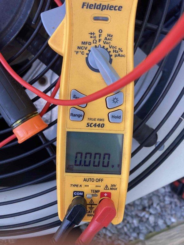 # AC NOT BLOWING 13+2-689

Responded to no cooling complaint on residential air conditioning system. Upon arrival, found outdoor condenser unit with fan motor inoperative. Performed electrical diagnostics using multimeter to test capacitor and verify power supply to fan motor. Measured capacitance reading of 0.000 MFD on run capacitor, indicating complete capacitor failure. Replaced failed dual run capacitor with proper MFD-rated component. Verified fan motor operation and proper electrical values after replacement. Restored system to normal cooling operation and confirmed adequate airflow through condenser unit.