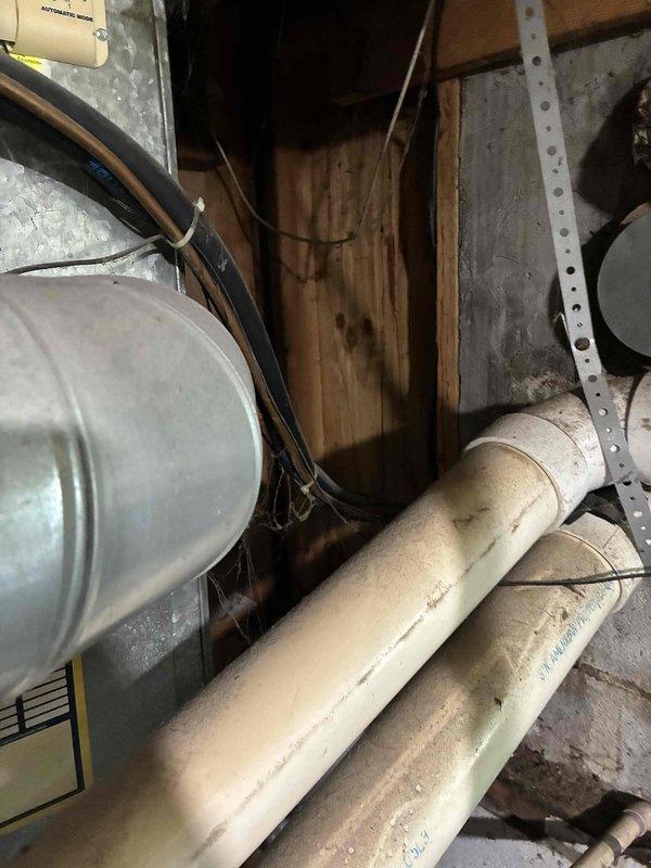 Conducted on-site assessment of non-operational air conditioning system with functional furnace in aging 2-4 ton HVAC installation. Evaluated existing equipment condition, electrical panel configuration with exposed circuit breakers, and mechanical space constraints within unfinished utility area featuring exposed framing and infrastructure. Documented current system layout including air handler unit, PVC drainage/vent lines, copper refrigerant piping, and electrical connections to support comprehensive replacement estimate for complete AC system upgrade.