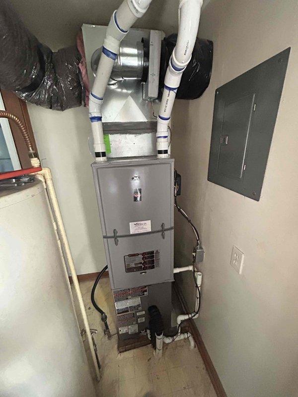 Completed installation of 3-ton air conditioning system with matching evaporator coil in residential utility room. Unit positioned on right side with proper clearances, all refrigerant lines connected, condensate drainage routed through PVC piping system, and electrical connections made to existing breaker panel. System tested and operational upon completion.
