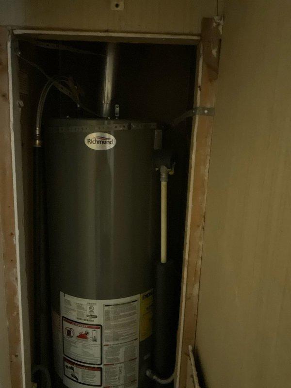 Conducted plumbing estimate for replacement of existing Richmond brand 30-gallon standard water heater in mobile home. Inspected current working unit installed in recessed wall cavity with natural draft venting, assessed existing plumbing connections including copper supply lines and flexible tubing, and evaluated installation space between wall studs to provide replacement specifications and recommendations.