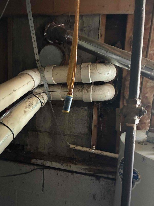Completed installation of 2.5-ton air conditioning system at rear of residence. Positioned outdoor condensing unit on concrete pad adjacent to building foundation with proper clearances, connected refrigerant lines with insulation running through window opening to indoor components located in basement utility area. Verified all electrical connections, tested system operation, and confirmed proper refrigerant charge and airflow.