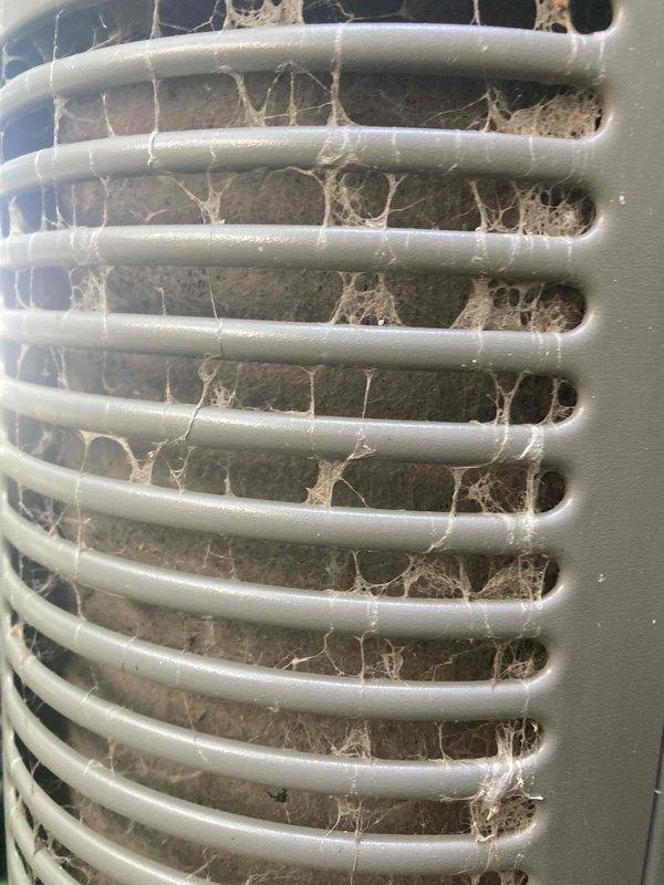 Responded to no cooling call on residential air conditioning system displaying red blinking fault indicator light. Upon inspection, found outdoor unit intake grille heavily obstructed with accumulated dust, lint, debris, and cobwebs restricting airflow to condenser coil. Cleaned and cleared ventilation grille to restore proper air circulation, documented conditions with photos, and system returned to normal operation after clearing blockage.