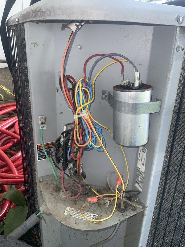# HVAC Service Completed

Responded to service call for 12-year-old residential air conditioning system with compressor running continuously and no cooling output affecting entire home. Upon arrival, removed outdoor unit access panel to inspect electrical and mechanical components. 

Performed visual inspection of contactor, capacitor, and electrical connections. Observed accumulated dirt and debris on interior components and exterior surfaces indicating extended service interval. Examined dual run capacitor mounted on right side of cabinet, noting proper physical mounting but requiring electrical testing. Inspected black contactor relay for proper operation and contact wear.

Conducted top-down inspection of compressor unit, identifying central motor shaft and internal chamber condition. Observed minor debris accumulation and surface wear consistent with 12-year operational age. Evaluated compressor mounting, internal components, and structural integrity of unit housing.

Documented e