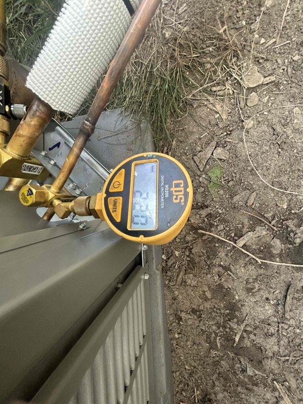 Restored power to HVAC system during warranty service call. System requires return visit to complete evacuation procedure and perform initial startup of air conditioning unit. Digital manifold gauges were connected to outdoor condensing unit to monitor system pressures and prepare for vacuum process.