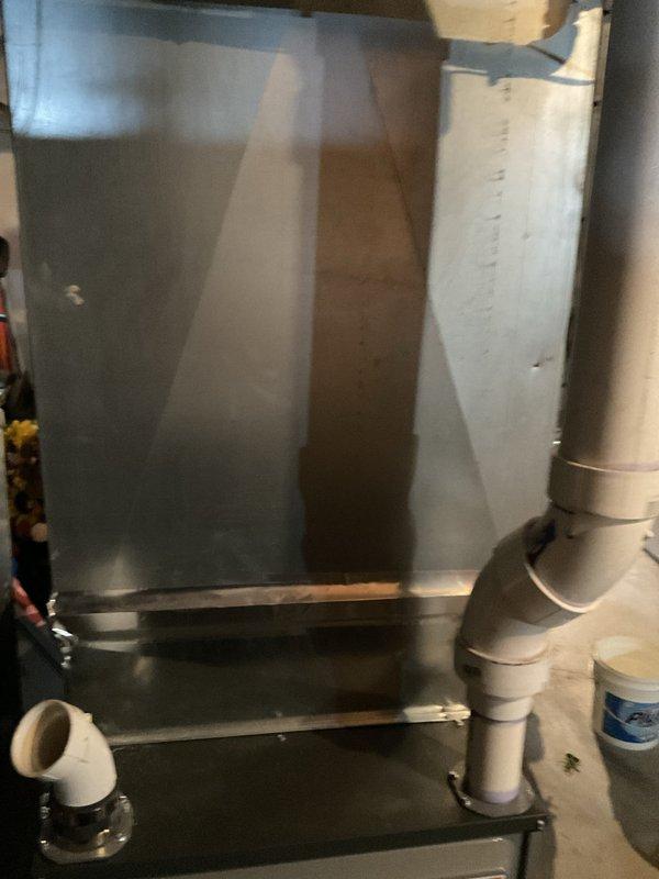 Conducted on-site evaluation of existing HVAC system for air conditioning replacement estimate. Inspected current air handler unit with metallic plenum assembly, verified condensate drain line configuration with white PVC piping, and assessed overall system condition in mechanical room. Evaluated existing basement utility equipment including water storage tank with copper connections and wall-mounted gray HVAC component with ventilation slots. Documented equipment specifications, spatial constraints, and installation requirements through detailed photographic documentation to provide accurate replacement system recommendations and sizing calculations for new air conditioning unit.