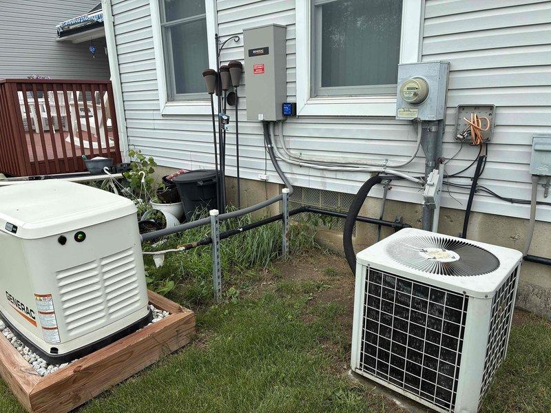 Conducted on-site evaluation for HVAC system replacement at residential property. Assessed existing exterior air conditioning condenser unit and documented current equipment configuration including standby Generac generator, electrical connections, and meter placement. Photographed basement utility area to evaluate water heater and existing mechanical systems for compatibility with proposed HVAC replacement equipment.