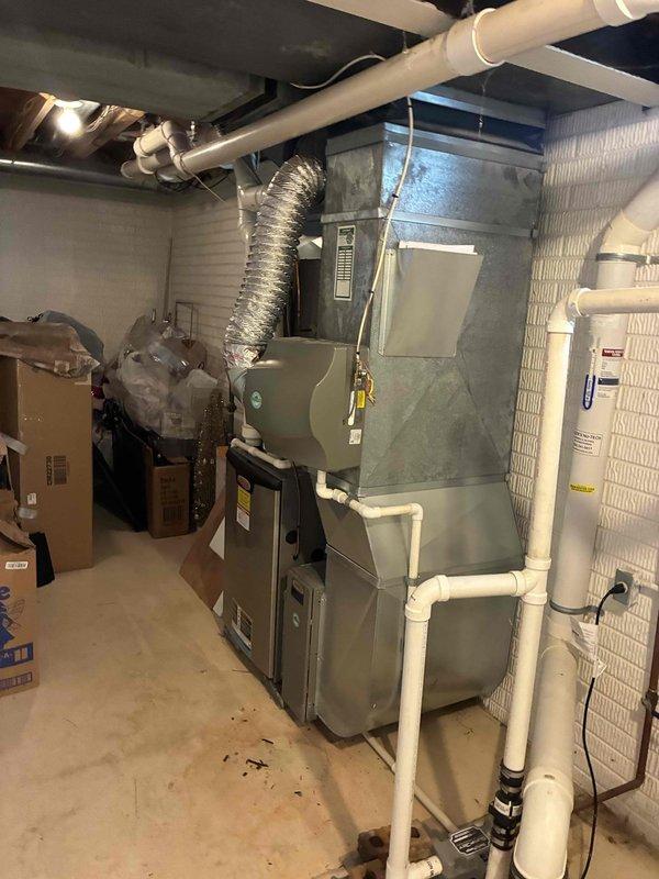 Conducted comprehensive assessment of existing HVAC system and water heater in basement mechanical room for replacement estimate. Documented current equipment configuration including gray metal furnace/air handler unit with associated PVC drainage lines, aluminum flex duct connections, and integrated ductwork system. Evaluated water heater installation and surrounding utility infrastructure including electrical components and plumbing connections. Captured detailed photographic documentation of equipment specifications, manufacturer labels, and existing installation conditions to develop accurate system replacement quote.