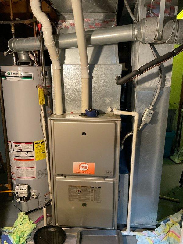 Provided estimate for complete HVAC system replacement including 16-year-old Payne furnace and outdoor AC condenser unit. Current air conditioning system is operational but experiencing refrigerant leak causing water damage and basement flooding. Equipment located in basement mechanical room with outdoor condenser positioned on concrete pad adjacent to home exterior.