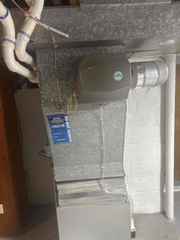 Completed full HVAC system installation including a 70,000 BTU furnace and 2-ton air conditioning unit in basement mechanical room. Installed new furnace with proper venting through PVC piping system secured to cinder block walls, connected refrigerant lines and metal ductwork for distribution system. Added humidifier to system and reconnected all necessary utilities. All drainage lines properly installed and secured with appropriate mounting hardware. Equipment positioned on platform base with all components operational and ready for use.