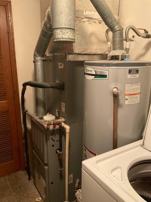 Conducted on-site evaluation for HVAC system replacement estimate in residential utility room. Documented existing equipment including gray metal furnace unit with galvanized ductwork system and A.O. Smith water heater with venting assembly. Recorded manufacturer model numbers and specifications from both furnace and air conditioning units for replacement quotation purposes. Photographed current installation configuration, including ductwork connections, piping arrangements, and equipment placement to ensure accurate system sizing and proper replacement planning.