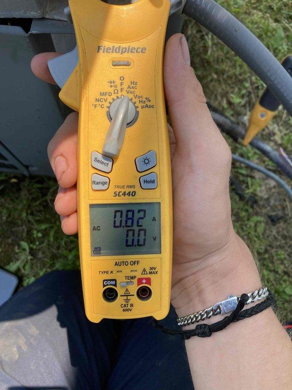 Responded to no cooling complaint on 10+ year old air conditioning system. Upon arrival, found unit running but blowing warm air. Performed electrical diagnostics using clamp meter, measuring 0.82 amps current draw and 0.0 volts at compressor circuit. Measured supply air temperature at 15.6°F, indicating extremely low refrigerant charge or complete loss of refrigerant. Low amp draw and voltage readings consistent with compressor not operating under load due to insufficient refrigerant pressure. System requires refrigerant leak detection, repair, and recharge to restore cooling operation.