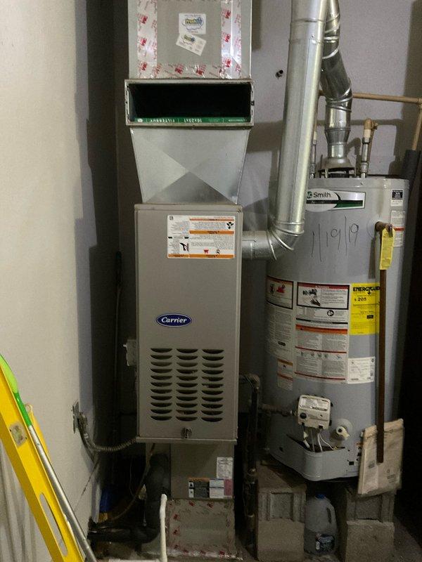Conducted on-site assessment of existing HVAC system to provide replacement estimate. Documented current Carrier furnace unit and outdoor air conditioning condenser with serial number identification for equipment specifications. Photographed existing equipment configuration including furnace installation dated from 2019, water heater proximity, venting arrangements, and outdoor condenser placement on concrete pad. Evaluated system accessibility, clearances, and existing ductwork connections to determine replacement requirements and scope of work for complete HVAC system upgrade proposal.