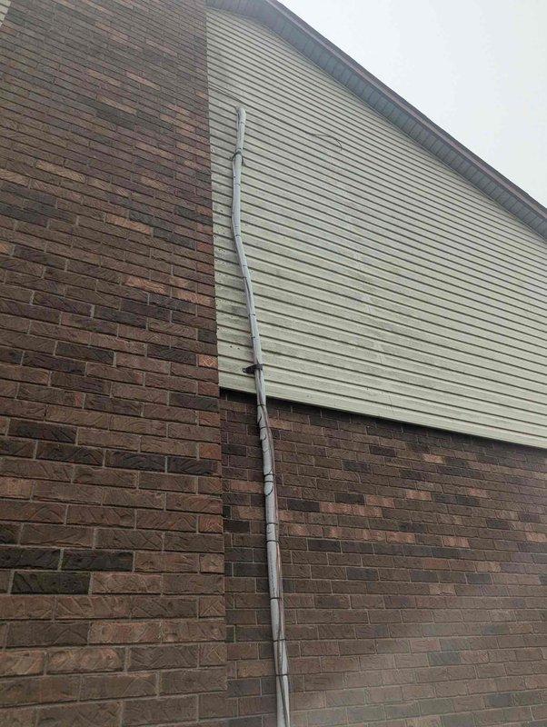 Completed final installation of HVAC air handler unit in attic space with associated ductwork and insulation. Installed exterior PVC condensate drain line along building exterior corner, running from attic through brick and siding sections to ground level. Verified proper air handler positioning, secured flexible ductwork connections, and ensured reflective insulated duct runs were properly sealed and supported. Confirmed condensate drain line was securely mounted with appropriate brackets and draining properly. System tested and operational upon completion of warranty work.
