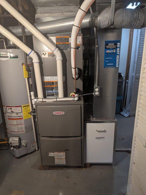 Completed full HVAC system installation including a 90,000 BTU Lennox furnace and 3-ton air conditioning unit positioned in the left side yard. The mechanical equipment was installed in the basement utility area with proper ductwork configuration, while the outdoor condenser unit was set on the side yard with appropriate PVC condensate drainage lines routed through the foundation landscaping. All components were connected, tested, and verified operational upon completion.