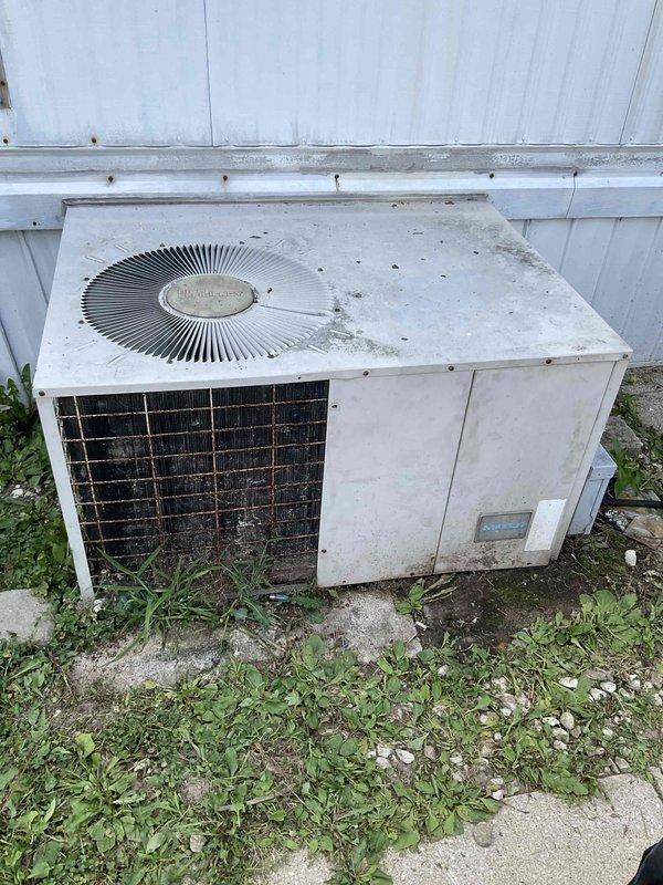 Responded to emergency no-cool call for outdoor condensing unit that would not start. Upon arrival, found older system with significant weathering, dirt accumulation, and visible corrosion on exterior components and grille work. Unit showed signs of deferred maintenance with vegetation overgrowth around base and debris on top surface. Performed diagnostic evaluation to determine cause of failure and provided customer with findings and repair options to restore cooling operation.