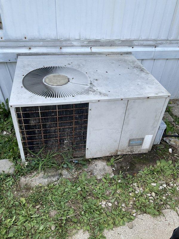 Responded to emergency no-cool call for outdoor condensing unit that would not start. Upon arrival, found older system with significant weathering, dirt accumulation, and visible corrosion on exterior components and grille work. Unit showed signs of deferred maintenance with vegetation overgrowth around base and debris on top surface. Performed diagnostic evaluation to determine cause of failure and provided customer with findings and repair options to restore cooling operation.
