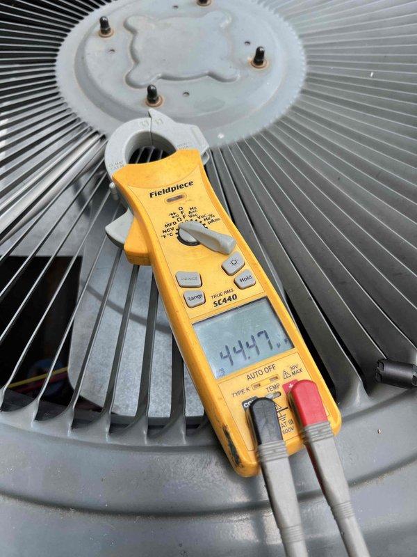 Completed AC Club preventive maintenance agreement visit on residential heat pump system. Performed comprehensive system diagnostics using digital multimeter, recording voltage readings of 92.4V and 447V at key electrical test points to verify proper power supply and compressor operation. Inspected outdoor condenser unit including fan motor assembly and condenser coil fins, confirming all components operating within normal parameters.