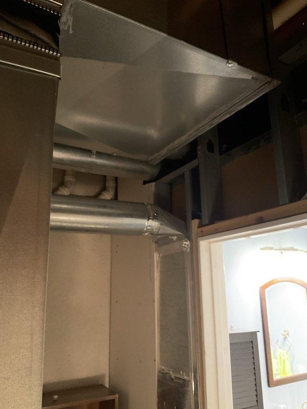 Responded to no cooling complaint with concerns about temperature imbalances between basement and upper floor. Upon inspection, found issues with the existing ductwork and ventilation system serving a multi-level structure. Documented the commercial-grade exhaust hood installation and associated ductwork routing, noting the system configuration that was contributing to inadequate air distribution throughout the building. Identified structural modifications and unfinished areas around doorways that were affecting proper airflow and thermal envelope integrity, resulting in the basement overcooling while the top floor remained too warm.
