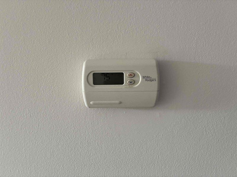 Conducted on-site assessment for air conditioning system replacement. Evaluated existing White-Rodgers thermostat and outdoor electrical components including junction box, control switch, and electrical panel mounted on exterior wall. Documented current equipment condition and provided comprehensive replacement quote for new AC system.