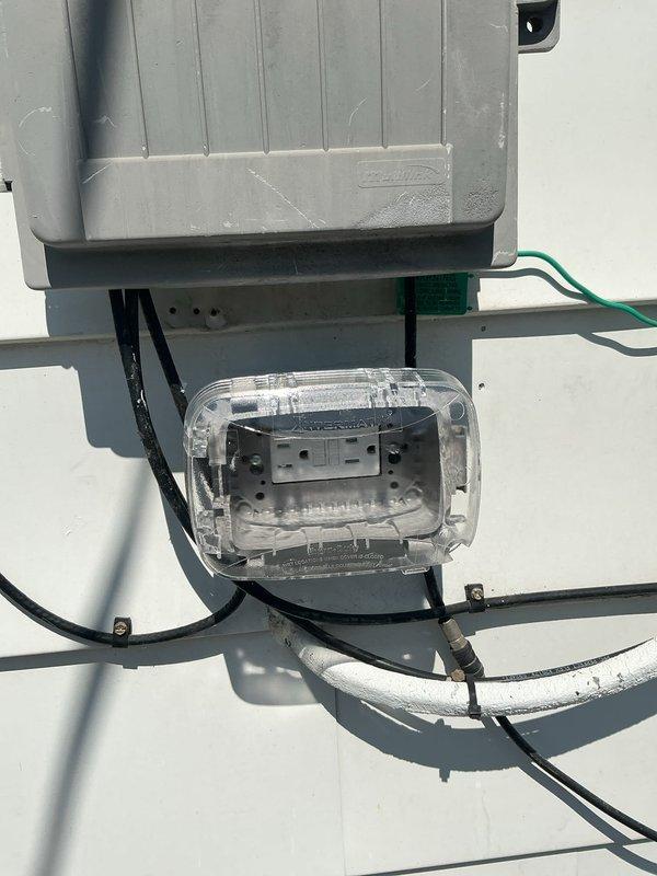 Installed GFCI protection for exterior electrical system at residential property. Mounted weatherproof junction box with clear cover below existing electrical panel enclosure on exterior wall, running appropriate conduit connections between boxes to provide ground fault circuit interruption for outdoor outlets and equipment. All electrical connections completed per code requirements for exterior installations.
