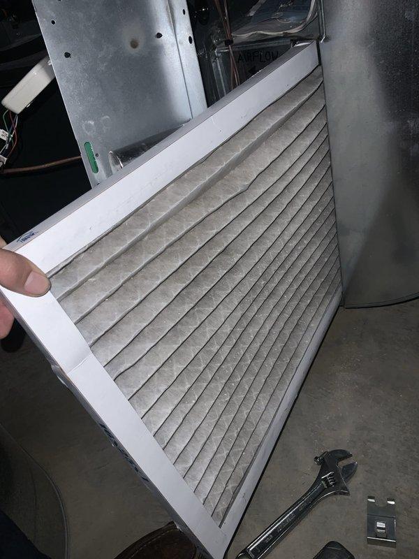 Completed preventative maintenance agreement visit for air conditioning system. Inspected and removed dirty air filter showing significant dust accumulation on pleated media, indicating proper filtration operation. Examined air handler components including curved metal plenum with vertical damper assembly, confirming proper structural condition and airflow control mechanisms functioning as designed.