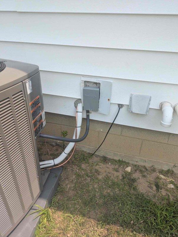 Completed installation of 2-ton air conditioning system at rear of residence, mechanical components only. Mounted outdoor condenser unit on pad against exterior wall with proper clearances, installed electrical disconnect box and associated conduit for power supply, and ran refrigerant lines with PVC drain piping to connect with existing furnace system in basement. Connected AC coil to furnace plenum, established proper refrigerant charge, verified electrical connections meet code requirements, and tested system operation to ensure proper cooling performance and airflow.