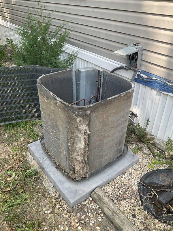 Responded to no cooling complaint on outdoor condensing unit. Upon arrival, found system inoperative with heavily weathered exterior showing significant corrosion and rust staining. Performed diagnostic evaluation of unit, inspected electrical connections at disconnect box, and assessed internal components including condenser coils. Unit exhibited extensive age-related deterioration despite being under 10 years old, with visible environmental damage to exterior panels and evidence of poor drainage around concrete pad contributing to accelerated corrosion. Completed system assessment and provided findings to customer regarding equipment condition and cooling failure.