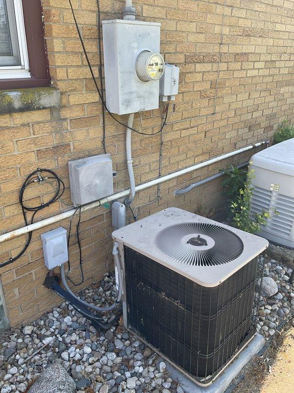 Conducted comprehensive estimate for complete HVAC system replacement of 10-12 year old equipment currently operational but nearing end of service life. Evaluated existing furnace installation in basement utility area with vertical PVC venting system and associated drainage piping, as well as outdoor condensing unit positioned on concrete pad with river rock landscaping and electrical service connections via wall-mounted meter and conduit system.