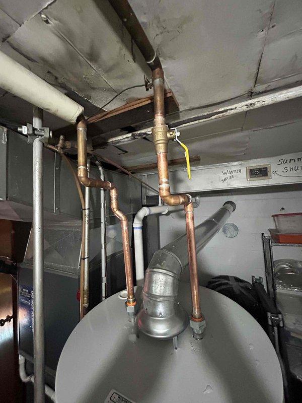 Completed mechanical-only installation of tanked water heater in basement utility area with reconnection of existing copper supply and distribution piping. Unit was positioned in mechanical room, all plumbing connections were made to the top-mounted inlet and outlet ports, and system was tested for proper operation. Installation was performed as a payment-upon-completion service with mechanical work only per customer request.
