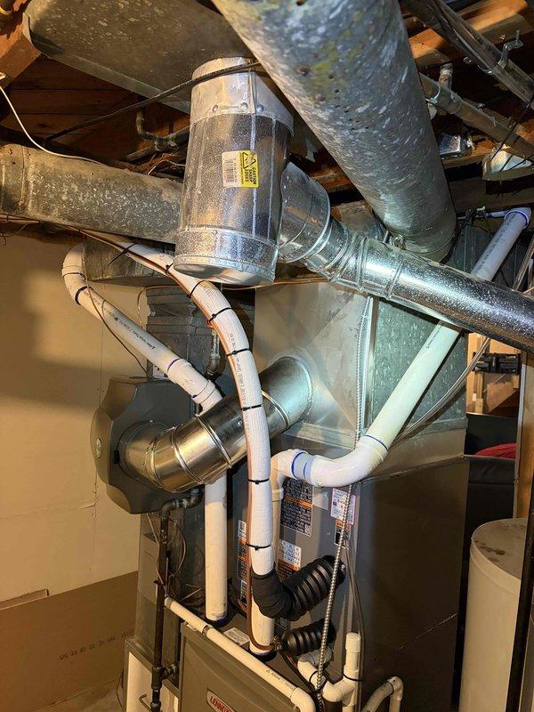 Completed full HVAC system installation including a Lennox 70,000 BTU furnace, 2-ton air conditioning unit with rear discharge configuration, and whole-home humidifier. Performed all mechanical and electrical connections, installed condensate drainage piping using white PVC, and routed flexible ductwork to integrate with existing distribution system. Connected air handler unit with insulated supply ducts, secured all ductwork with proper strapping, and verified proper venting through metal exhaust piping. System tested and operational upon completion.