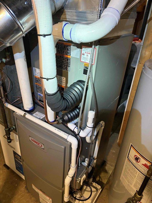 Completed full HVAC system installation including a Lennox 70,000 BTU furnace, 2-ton air conditioning unit with rear discharge configuration, and whole-home humidifier. Performed all mechanical and electrical connections, installed condensate drainage piping using white PVC, and routed flexible ductwork to integrate with existing distribution system. Connected air handler unit with insulated supply ducts, secured all ductwork with proper strapping, and verified proper venting through metal exhaust piping. System tested and operational upon completion.