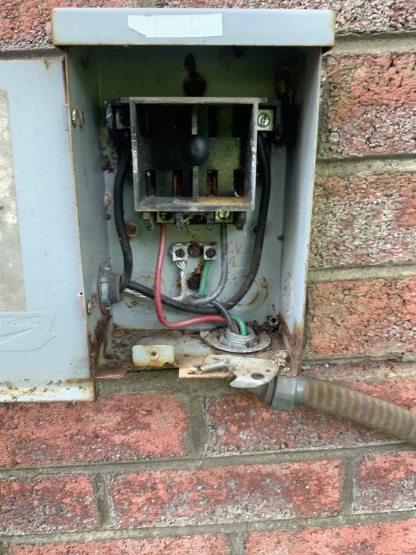 # HVAC Service Report - No Cool Condition

Responded to service call for air conditioning system not cooling on unit over 10 years old. Upon arrival, performed visual inspection of outdoor condensing unit and electrical components. Found outdoor disconnect box mounted on exterior brick wall showing extensive weathering, rust, and corrosion throughout interior components. Circuit breaker and contactor housing displayed significant deterioration with rust stains streaking from connection points and exposed bare metal where paint had chipped away.

Opened equipment panels to inspect internal electrical connections and components. Located contactor assembly with brass terminal block showing signs of age and wear. Examined all wire connections including power supply wires and control circuit wiring. Found accumulated dirt, grime, and debris throughout equipment interior affecting multiple components. Metal surfaces displayed considerable discoloration and staining consistent with age and en