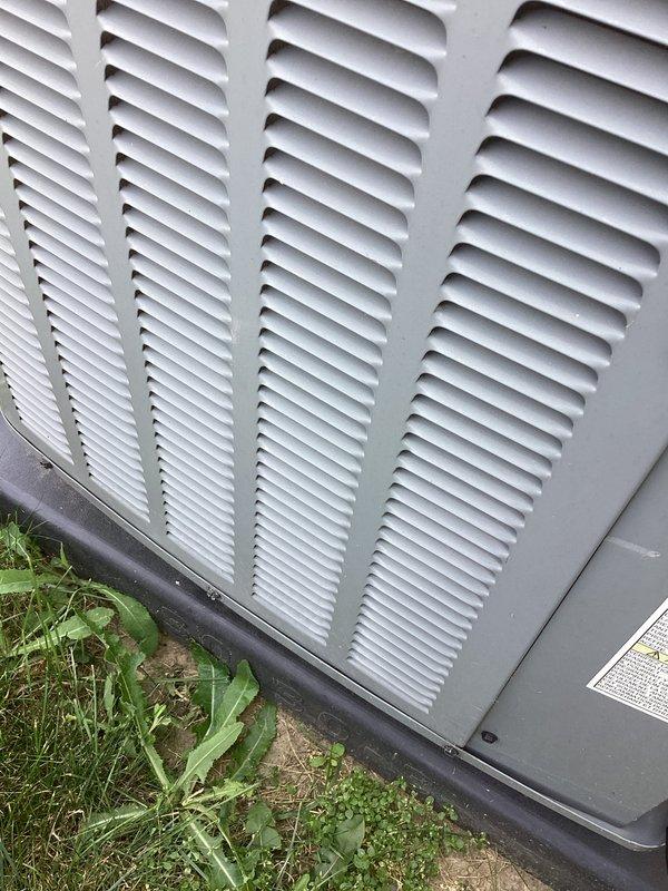 # AC NOT WORKING 12-489

Responded to no cooling call on outdoor condensing unit. Upon arrival, performed visual inspection of exterior HVAC equipment. Unit appeared to be 10+ years old based on condition and weathering patterns. Exterior casing showed normal aging consistent with outdoor installation, with louvers intact and properly aligned.

Documented equipment condition through photographs for service records. Unit positioned on ground-level pad with adequate clearance for airflow. Ventilation grilles and horizontal louvers clean and unobstructed, allowing proper air circulation to internal components. No visible signs of physical damage, severe corrosion, or structural compromise to cabinet or protective casing.

Noted manufacturer identification label present on unit exterior for reference. Surrounding area showed vegetation growth near base, which could potentially restrict airflow if left unmanaged. Black protective base trim intact and properly seated against mounting surface