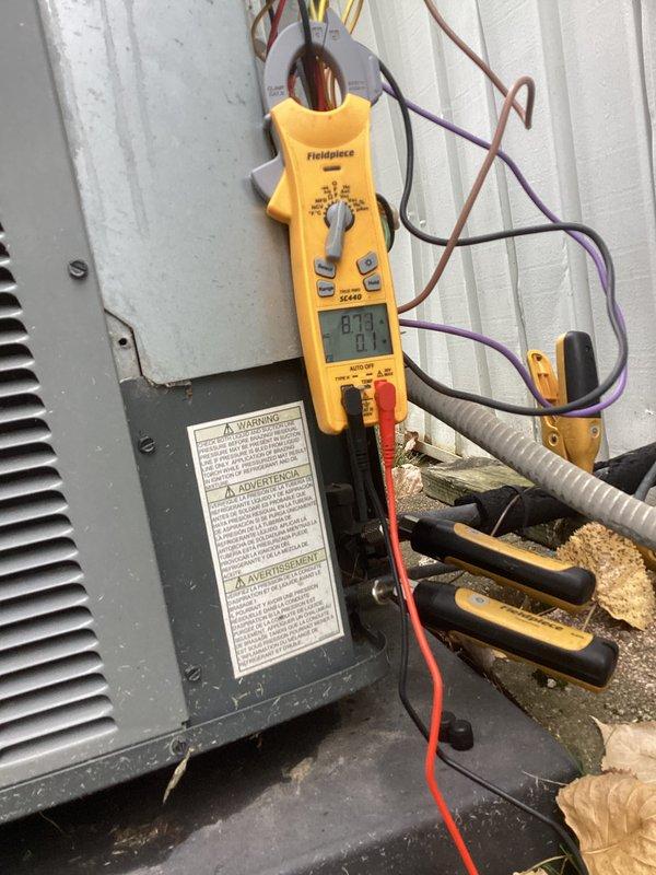 # HVAC Service Report - No Cool Condition

Responded to emergency service call for air conditioning system not cooling adequately with rising indoor temperatures. Upon arrival, performed visual inspection of outdoor condensing unit and found significant debris accumulation around compressor base, including leaves, dirt, and standing water creating obstruction to proper airflow and drainage.

Conducted electrical diagnostics using clamp meter to measure amperage draw on compressor circuit. Recorded readings to verify compressor operation and compare against manufacturer specifications. Inspected refrigerant lines, electrical connections, and capacitor for proper function and signs of wear.

Identified debris buildup as contributing factor to reduced cooling efficiency. Removed accumulated organic matter and standing water from compressor housing base to restore proper drainage and prevent future corrosion. Cleaned area around compressor to eliminate airflow restrictions.

Verified all e