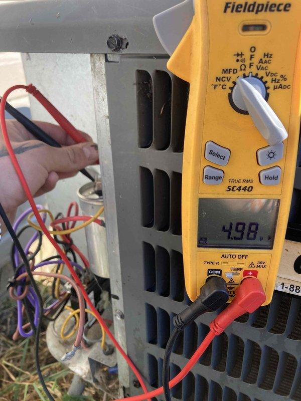 Completed prepaid air conditioner tune-up maintenance on a Goodman GSX130361EB unit utilizing R-410A refrigerant. Performed comprehensive system diagnostics including electrical testing with digital multimeter, verifying voltage readings at 4.98 volts at measured components, inspecting capacitor connections, and evaluating all electrical terminals and wiring connections. Confirmed unit specifications including compressor RLA 14.1, LRA 77, fan motor FLA 1.5 with 1/4 HP rating, and proper factory refrigerant charge of 64 ounces. All components operating within manufacturer specifications with no deficiencies noted during routine preventive maintenance inspection.