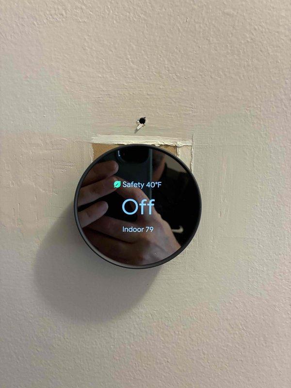 Conducted on-site evaluation for AC unit replacement. Assessed existing thermostat installation and wiring configuration, documenting current system setup including wire terminals and mounting condition. Evaluated smart thermostat currently in safety mode at 40°F with indoor temperature reading of 79°F, indicating potential system malfunction or improper operation requiring replacement estimate.
