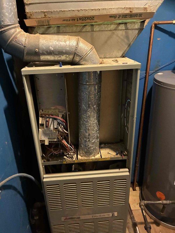 Completed comprehensive HVAC system evaluation for replacement estimate on existing American Standard Freedom 95 furnace installation. Documented current equipment condition including visible moisture accumulation on internal ductwork, assessed overall system configuration with copper refrigerant lines and electrical connections, and photographed installation setup to provide accurate replacement specifications for customer consideration.