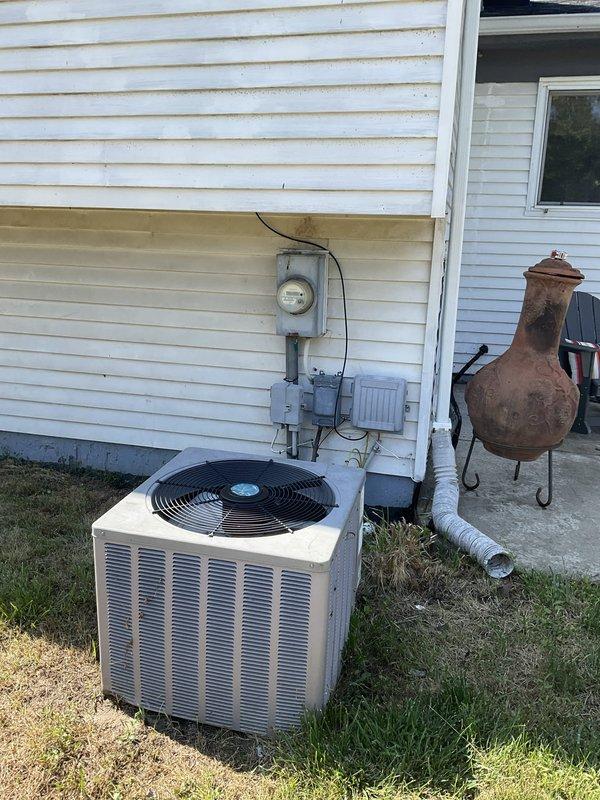 Conducted on-site evaluation of 20-year-old R22 air conditioning system that was no longer adequately cooling the residence. Documented existing Bryant furnace installation in basement utility area along with associated ductwork, condensate drainage lines, and electrical connections. Photographed outdoor condensing unit positioned on concrete pad with electrical meter and service connections. System assessment confirmed age-related performance decline and obsolete refrigerant type. Prepared replacement estimate for basic air conditioning system installation suitable for property transfer to future occupants.